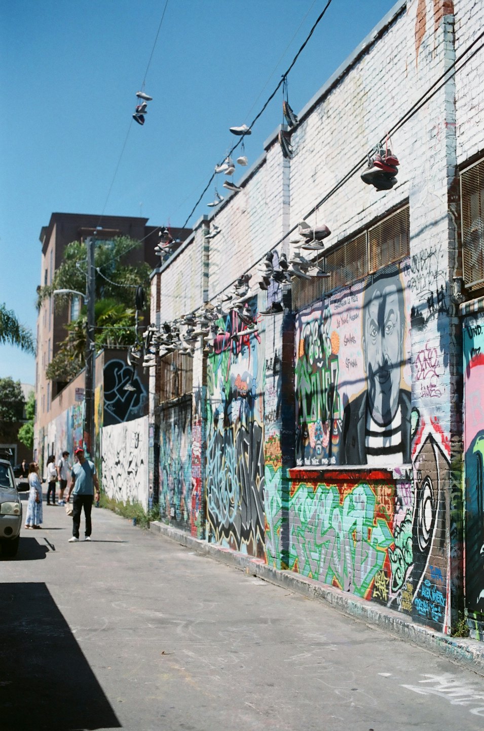 Peatones caminan por un callejón con coloridos murales de grafiti.