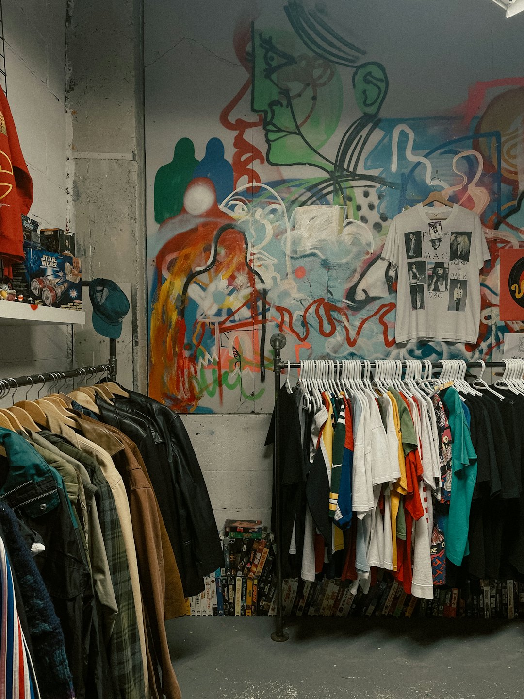 Estantes de ropa vintage en una tienda con arte de grafiti.