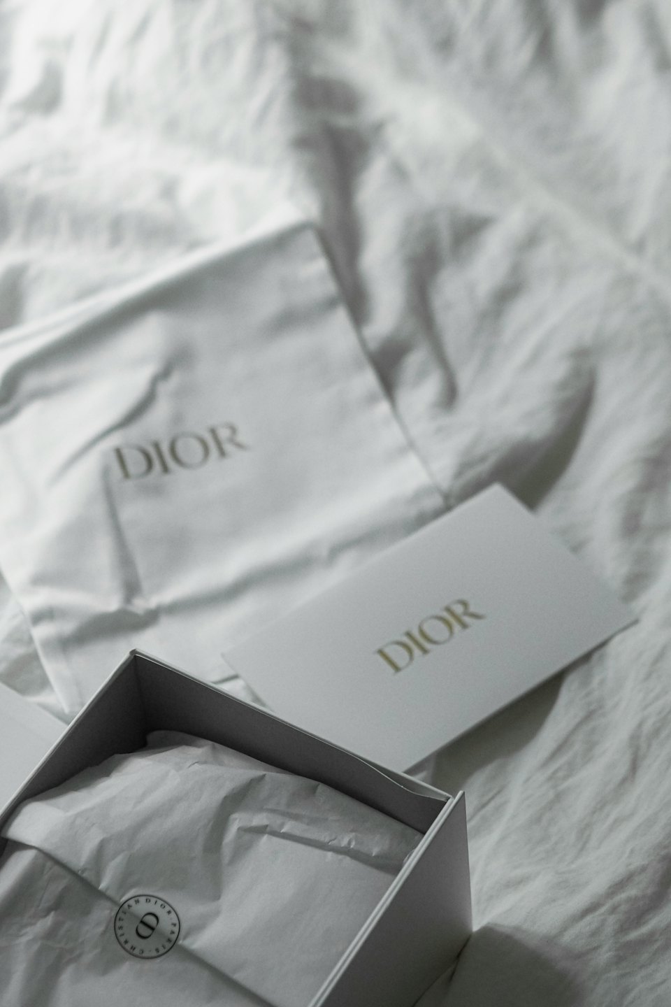 Cajas de marca de lujo y accesorios de tela dispuestos sobre tela blanca.