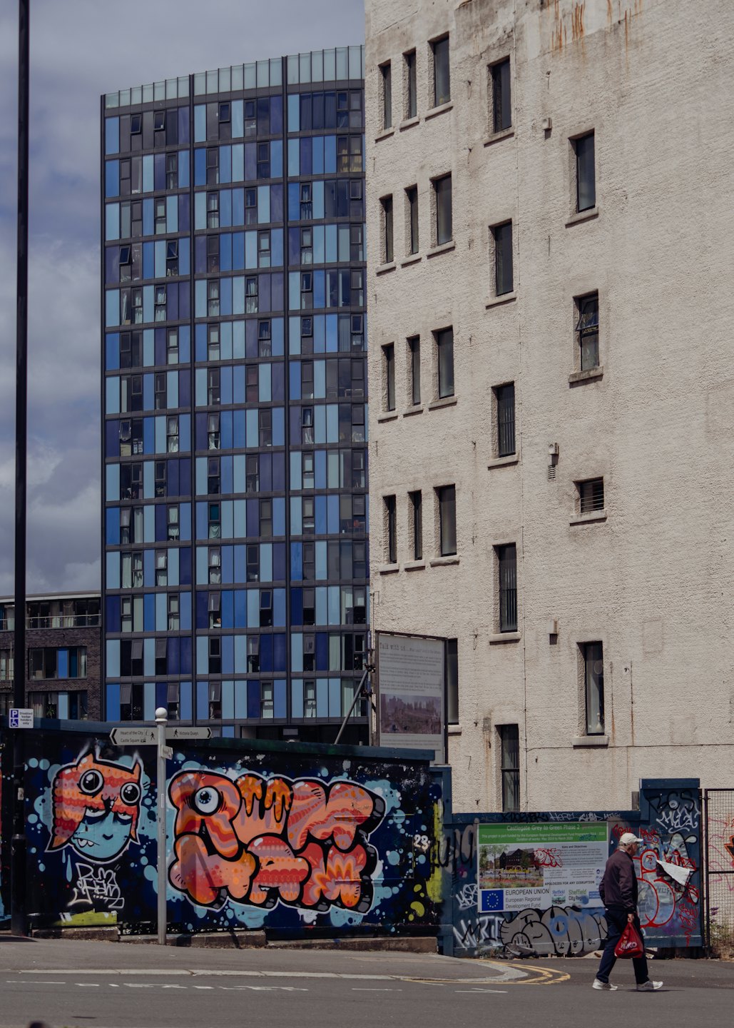 Hombre caminando frente a una pared cubierta de grafitis en una calle de la ciudad.